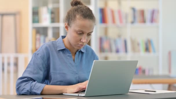 Professionell afrikansk kvinna som arbetar på laptop i biblioteket — Stockvideo