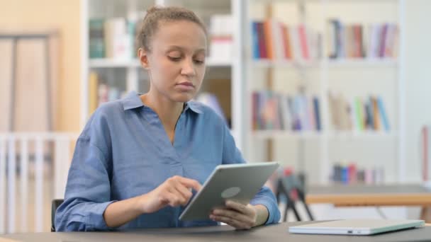 Afrikaanse vrouw reageert op mislukking op tablet in de bibliotheek — Stockvideo