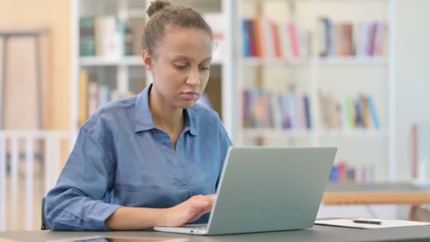 Sjuk afrikansk kvinna med laptop hosta i biblioteket — Stockvideo