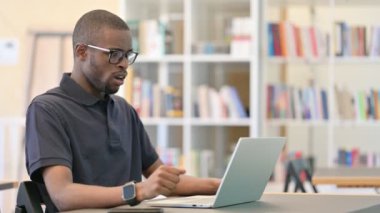 Dizüstü bilgisayarı olan endişeli Afrikalı genç adam laptopta şok geçiriyor.