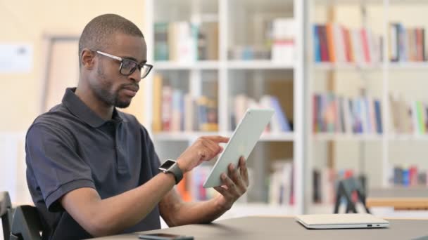 障害、図書館でタブレット上の損失を持つ若いアフリカ人男性 — ストック動画