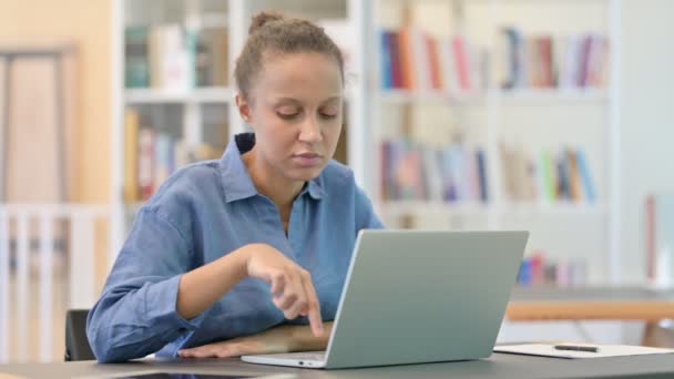 Mujer africana profesional haciendo videollamada en el ordenador portátil en la biblioteca — Vídeos de Stock