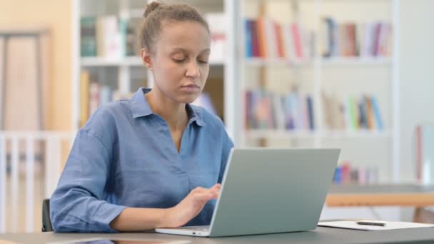 Stresszes afrikai nő Laptop amelynek fejfájás a könyvtárban — Stock videók