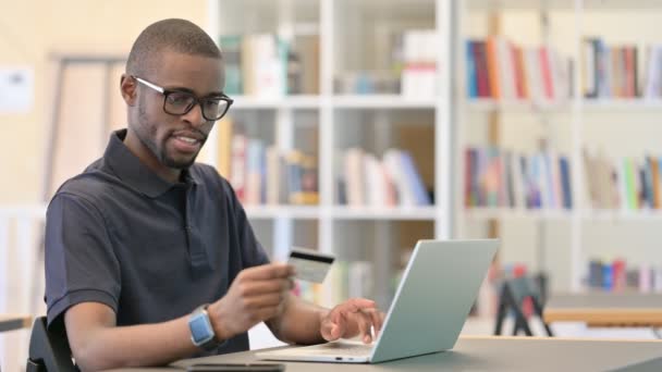 Sukces płatności online przez młodego Afrykanina na laptopie w biurze — Wideo stockowe