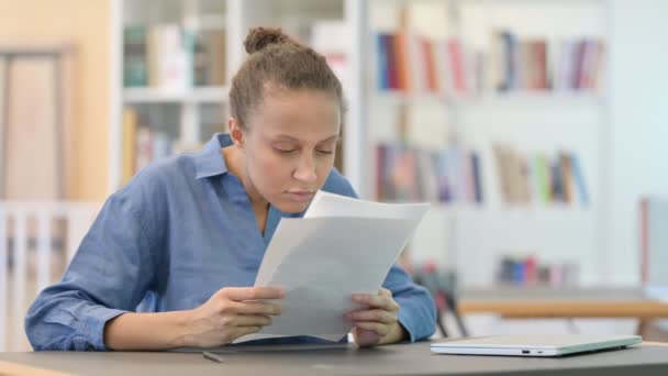 Ung afrikansk kvinna läser dokument i biblioteket — Stockvideo