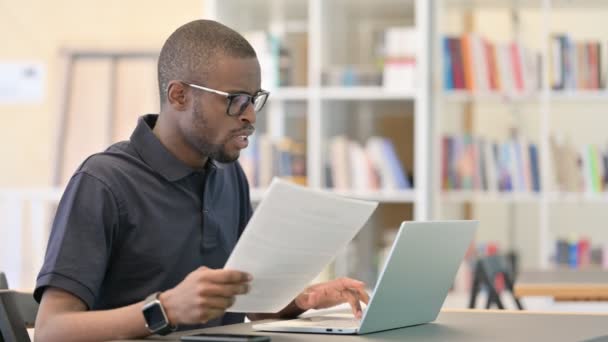 Afrikaanse man heeft verlies werken op laptop met documenten — Stockvideo