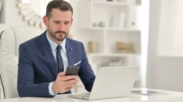 Profesjonalny biznesmen korzystający ze smartfona i laptopa w biurze — Wideo stockowe