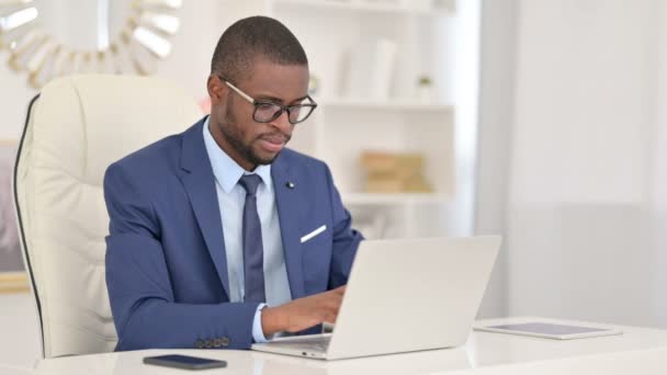 Joven empresario africano con portátil sonriendo a la cámara — Vídeo de stock