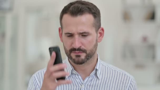 Retrato de un joven enojado discutiendo en un teléfono inteligente — Vídeos de Stock