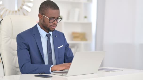 Aantrekkelijke jonge Afrikaanse zakenman werkt op Laptop in Office — Stockvideo