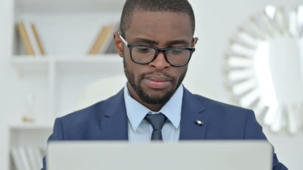 Retrato del empresario africano pensando y trabajando en el ordenador portátil — Vídeo de stock
