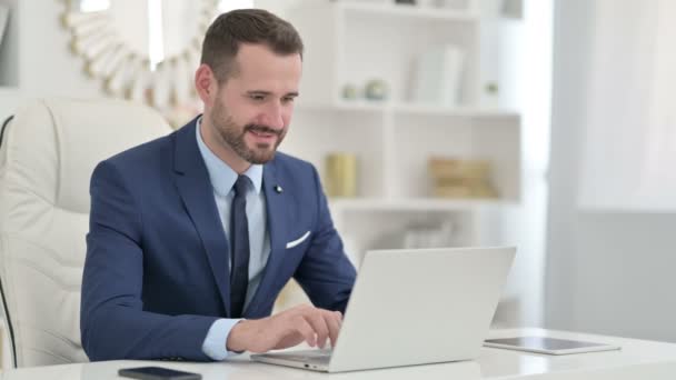 Biznesmen świętuje sukces na laptopie w biurze — Wideo stockowe