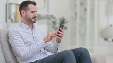 Evde akıllı telefon kullanan çekici genç adam. 