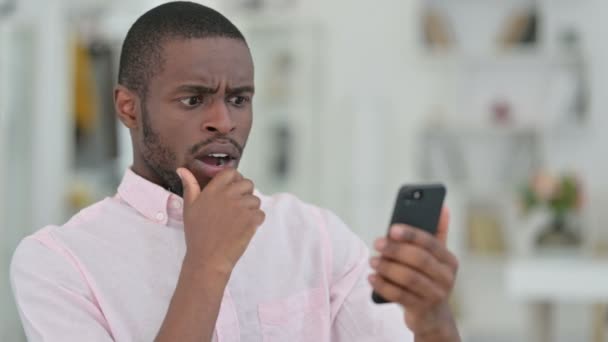 Retrato del hombre africano leyendo a la pérdida en el teléfono inteligente, el fracaso — Vídeo de stock