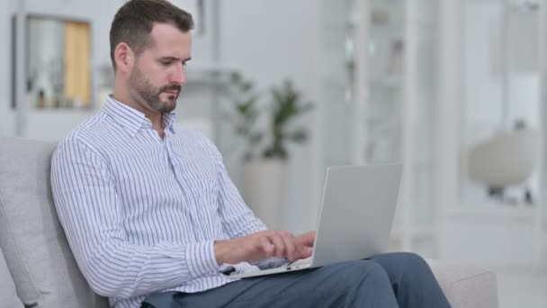 Moe jonge man met laptop met nekpijn thuis — Stockvideo