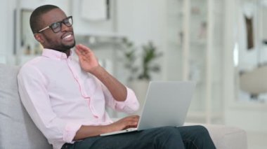 Dizüstü bilgisayarı olan yorgun Afrikalı genç adamın evinde boyun ağrısı var. 