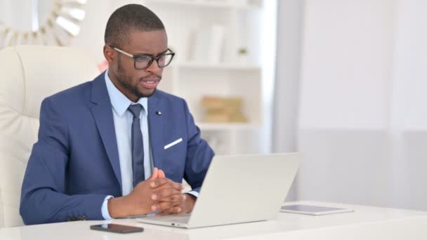 アフリカのビジネスマンがオフィスのノートパソコンでビデオ通話を行う — ストック動画