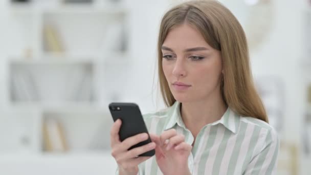 Porträt einer aufgeregten jungen Frau, die ihren Erfolg auf dem Smartphone feiert — Stockvideo