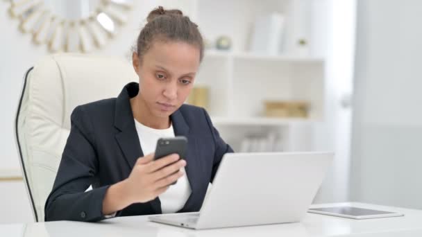 Empresária Africana usando Smartphone e Laptop no escritório — Vídeo de Stock