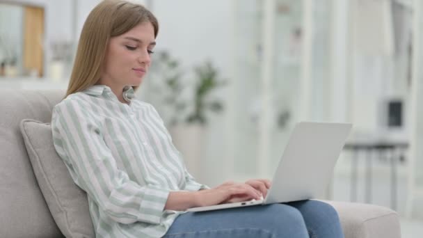 Junge Frau mit Laptop lächelt zu Hause in Kamera — Stockvideo