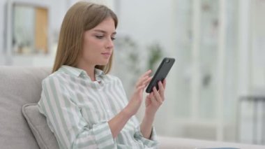 Evde akıllı telefon kullanan Ciddi Genç Kadın 