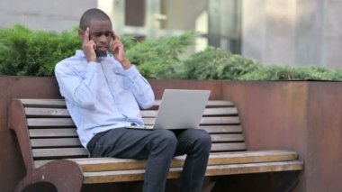 Laptop 'u olan genç Afrikalı adamın dışarıda başı ağrıyor. 