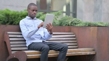 Açık havada oturan genç Afrikalı Tablet kullanıyor