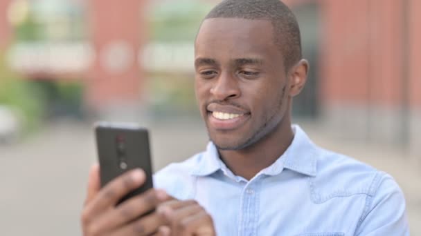 스마트폰을 사용하는 긍정적 인 아프리카 남자의 실외 초상화 — 비디오