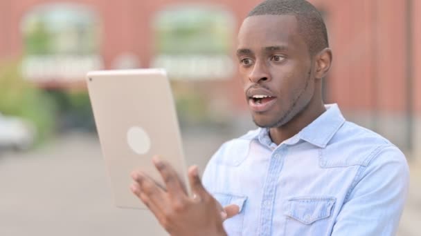 Ritratto all'aperto di un uomo africano eccitato che celebra il successo su tablet — Video Stock