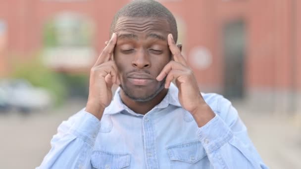 Retrato al aire libre de un joven africano cansado con dolor de cabeza — Vídeos de Stock
