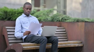 Belgeler ve Laptop üzerinde çalışan Afrikalı Adam 