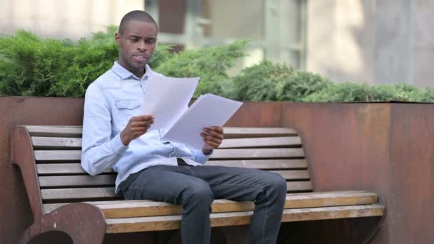 Homem Africano leitura Documentos sentados ao ar livre — Vídeo de Stock