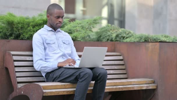 Волнующий африканский человек празднует успех на открытом воздухе ноутбука — стоковое видео