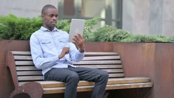 Hombre africano celebrando el éxito en la tableta al aire libre — Vídeos de Stock