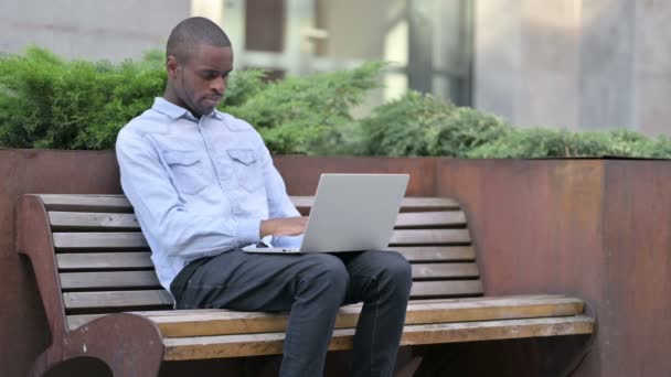 Afrikalı Adam Laptop 'u dışarıda düşünüyor ve kullanıyor — Stok video