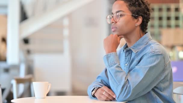 Mujer africana preocupada sentada en el café y pensando — Vídeos de Stock