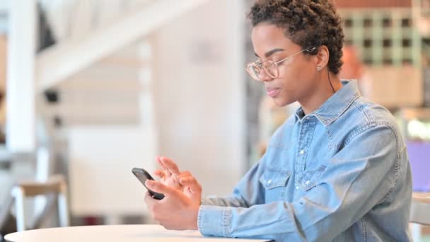 Mujer africana seria usando Smartphone en Café — Vídeos de Stock