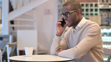Cafe 'de akıllı telefondan konuşan çekici Afrikalı adam. 