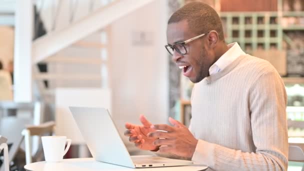 Opgewonden Afrikaanse man viert succes op laptop in Cafe — Stockvideo