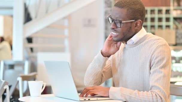 Cansado africano hombre con portátil tener dolor de cuello en el café — Vídeos de Stock