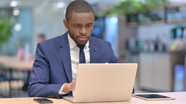 Empresario africano con portátil haciendo pulgares hacia abajo en la oficina — Vídeos de Stock