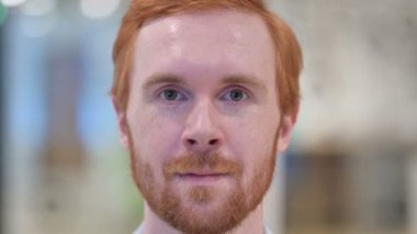 Kameraya bakan kızıl saçlı adamın gülen yüzünü kapatın.