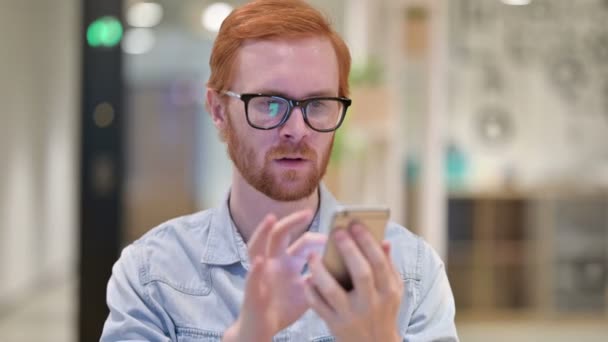 Portrett av ustabil rødhåret mann med tap på smarttelefon – stockvideo