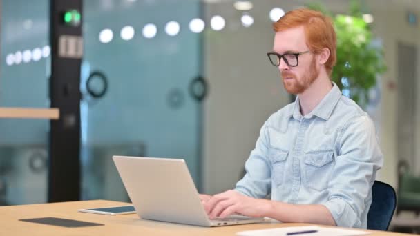 Focalisé Casual rousse homme travaillant sur ordinateur portable dans le bureau — Video