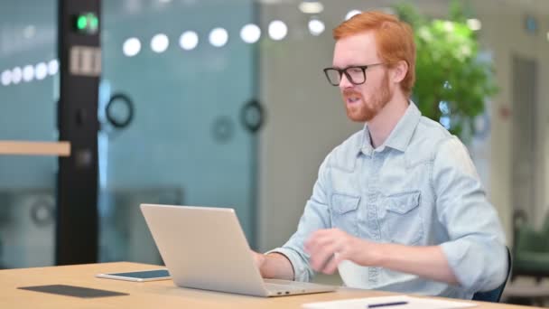 Случайный рыжий человек с ноутбуком с болями в спине в офисе — стоковое видео