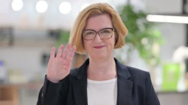 Neşeli yaşlı iş kadınının portresi Kameraya el sallıyor 