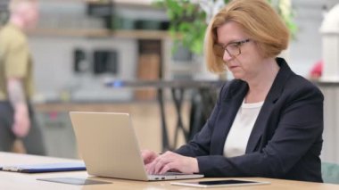 Ofisteki dizüstü bilgisayarda çalışan yaşlı iş kadını. 