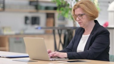 Dizüstü bilgisayarlı yaşlı iş kadını ofiste öksürüyor. 