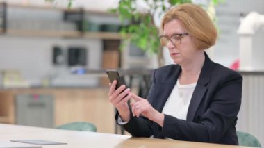 Ofiste akıllı telefon kullanan ciddi bir iş kadını. 