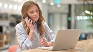 Dizüstü bilgisayarlı iş kadını Ofiste Smartphone 'da konuşuyor 